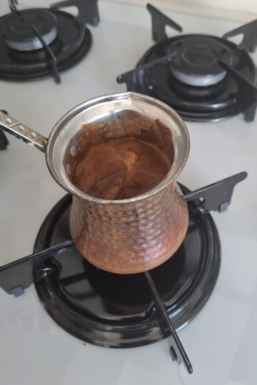 A photo showing Turkish coffee being boiled again after the foam has been removed